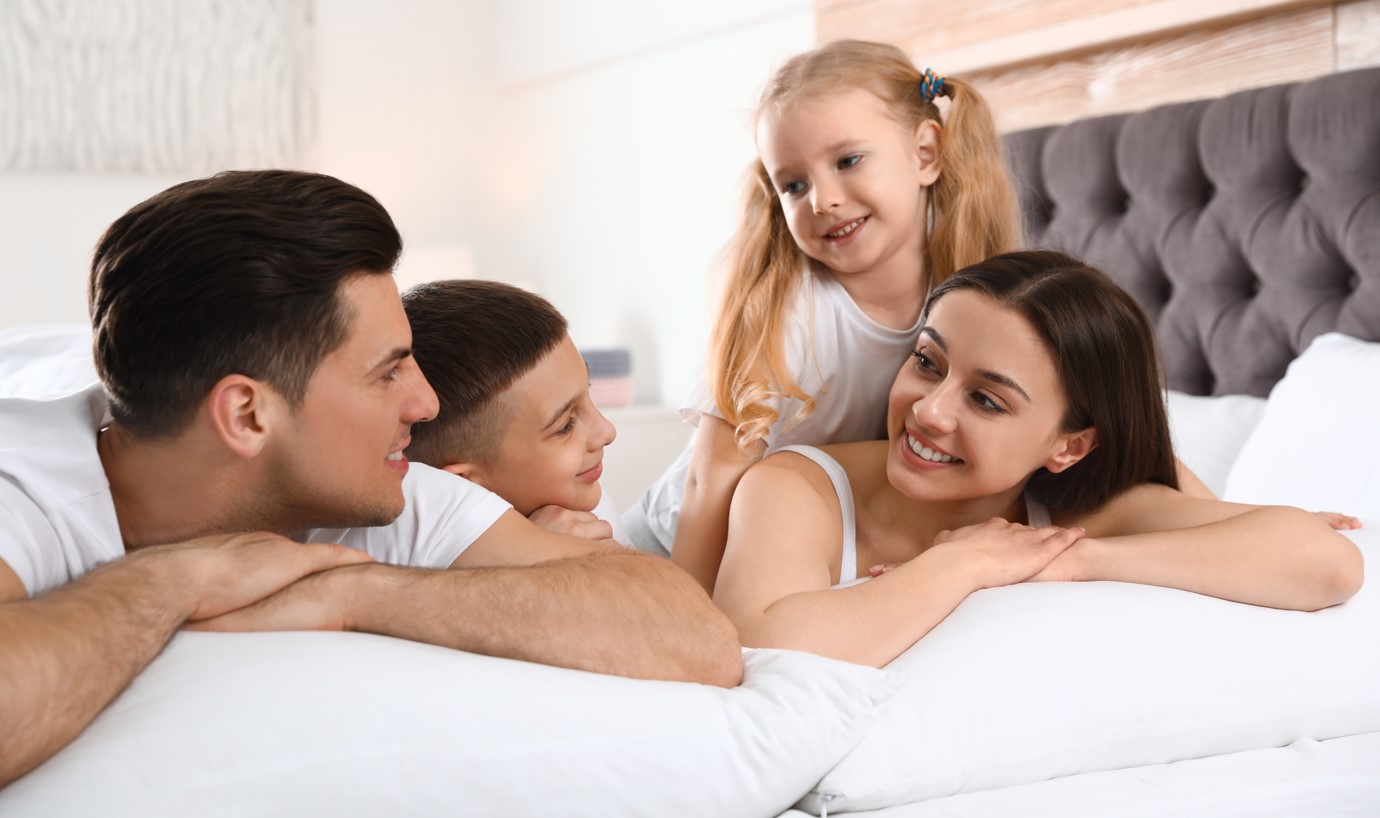 Happy young family together on large bed